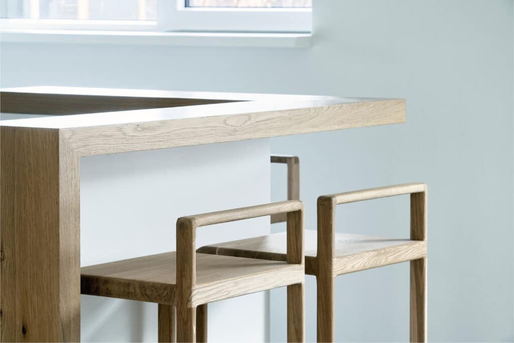 Twee houten barkrukken aan een maatwerk barblad van eikenhout in keuken Oudemirdum