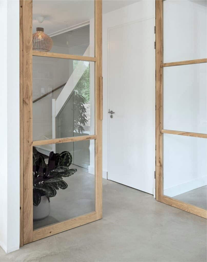 Eikenhouten taatsdeur met glas in moderne hal en zicht op trap