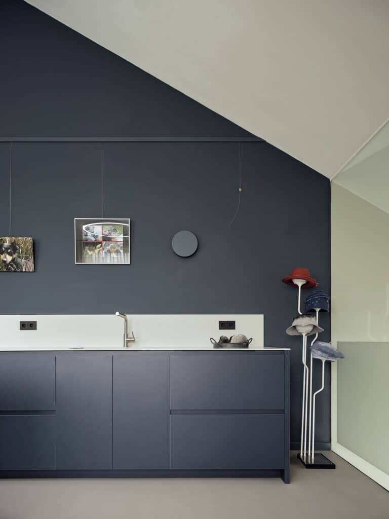 Stijlvolle bijkeuken met donkerblauwe kastenwand, witte achterwand en hoedenhouder
