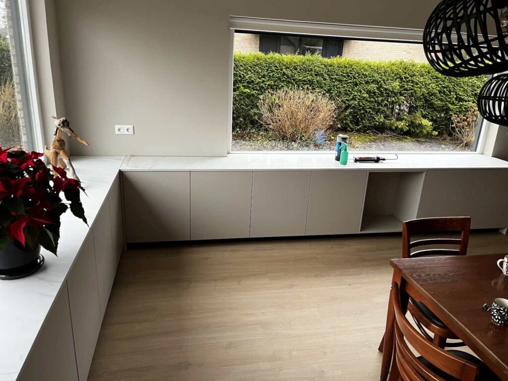 Moderne vensterbankkast in Heerenveen met opbergruimte, passend bij de lichte houten vloer en het minimalistische interieur.