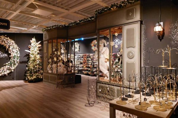 Interieur van een kerst boutique bij Intratuin met feestelijke verlichting, kerstbomen, decoratie en een etalage in klassieke stijl.