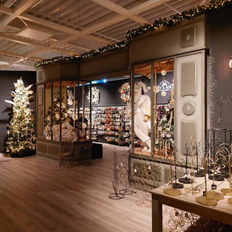 Interieur van een kerst boutique bij Intratuin met feestelijke verlichting, kerstbomen, decoratie en een etalage in klassieke stijl.