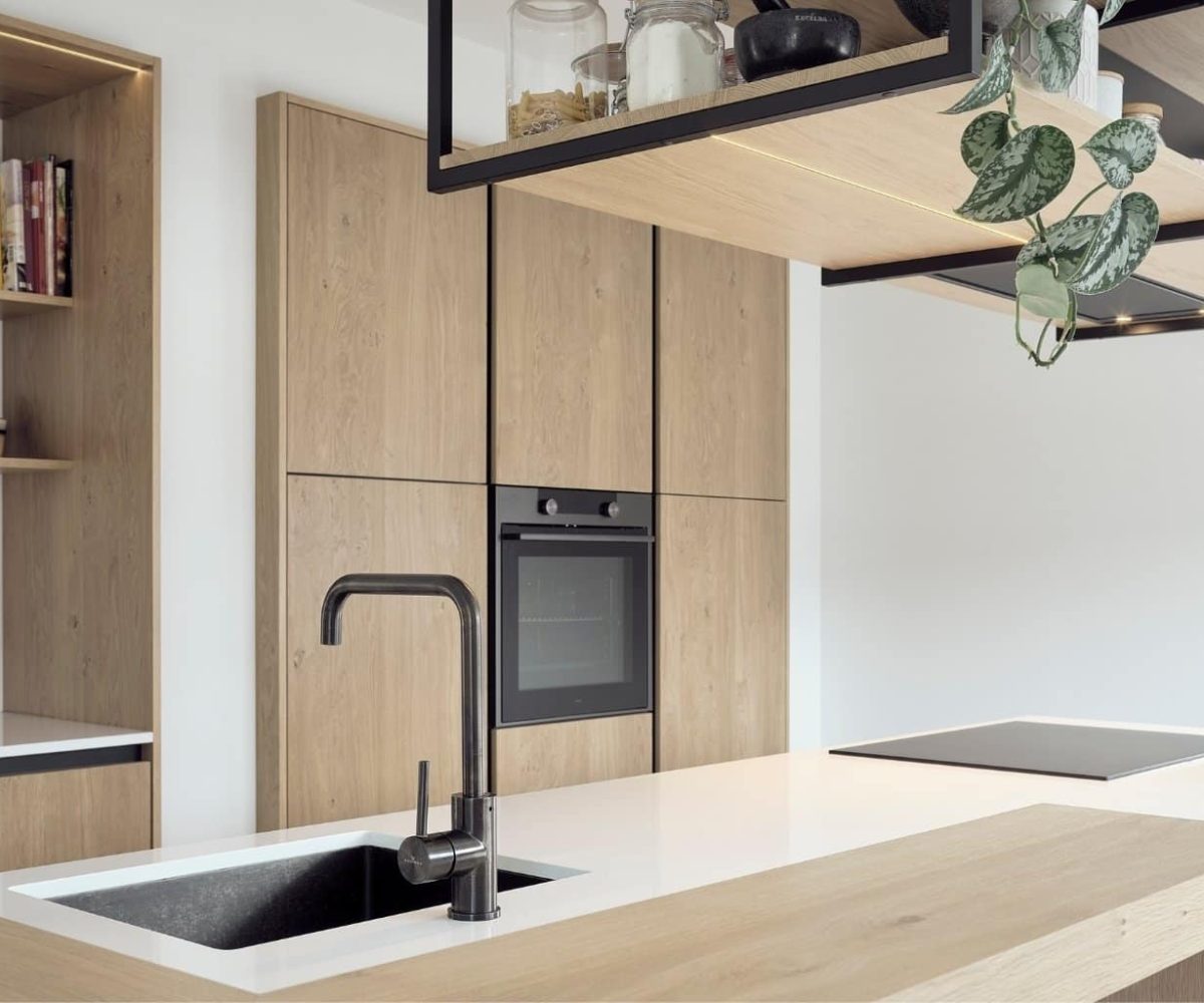 Maatwerk keuken in Oudemirdum met houten kastenwand, zwarte keukenkraan en wit aanrechtblad