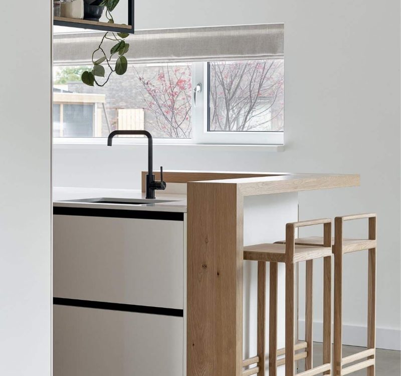 Compact keukenontwerp met ingebouwde bar en zwart keukenkraan
