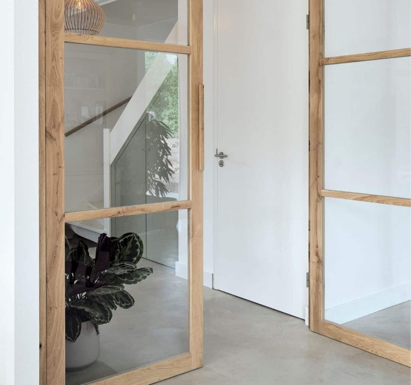 Eikenhouten taatsdeur met glas in moderne hal en zicht op trap