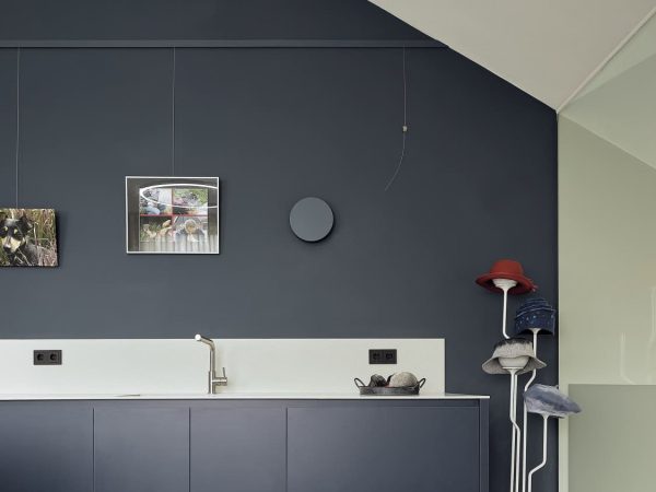 Stijlvolle bijkeuken met donkerblauwe kastenwand, witte achterwand en hoedenhouder