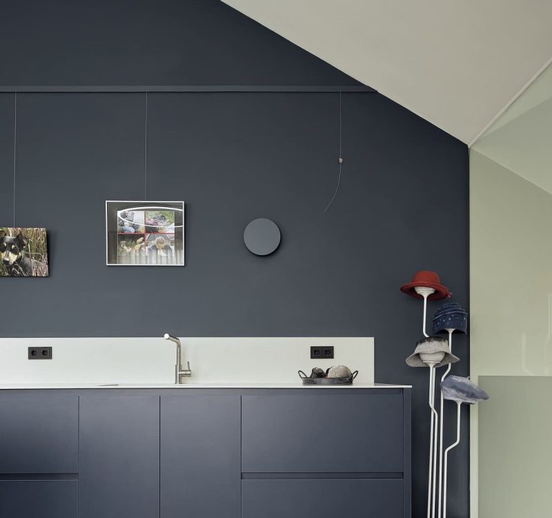 Stijlvolle bijkeuken met donkerblauwe kastenwand, witte achterwand en hoedenhouder
