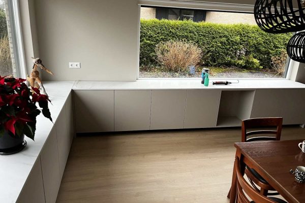 Moderne vensterbankkast in Heerenveen met opbergruimte, passend bij de lichte houten vloer en het minimalistische interieur.