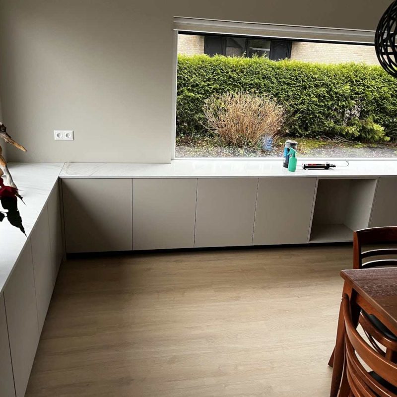 Moderne vensterbankkast in Heerenveen met opbergruimte, passend bij de lichte houten vloer en het minimalistische interieur.